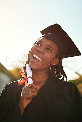 Buy stock photo Shot of a thoughtful young woman holding a diploma on graduation day