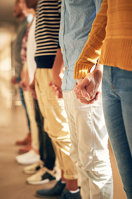 Buy stock photo Shot of a diverse group of people holding hands while standing in a line
