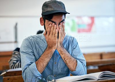 Buy stock photo Cropped shot of an university student covering his face in exhaustion in class