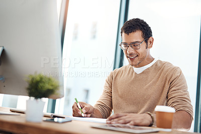 Buy stock photo Shot of a young designer writing notes while working at his desk in an office