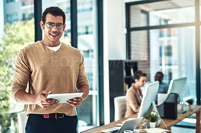 Buy stock photo Shot of a designer using his digital tablet with his colleagues blurred in the background