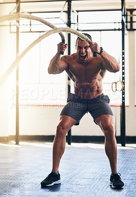Buy stock photo Shot of a muscular young man working out with heavy ropes at the gym