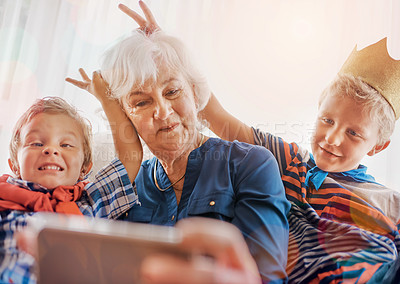 Buy stock photo Grandmother, grandchildren and boys with selfie for photography, picture or bonding together at home. Grandma, grandkids or young siblings with bunny ears for grandmom or memory on sofa at house