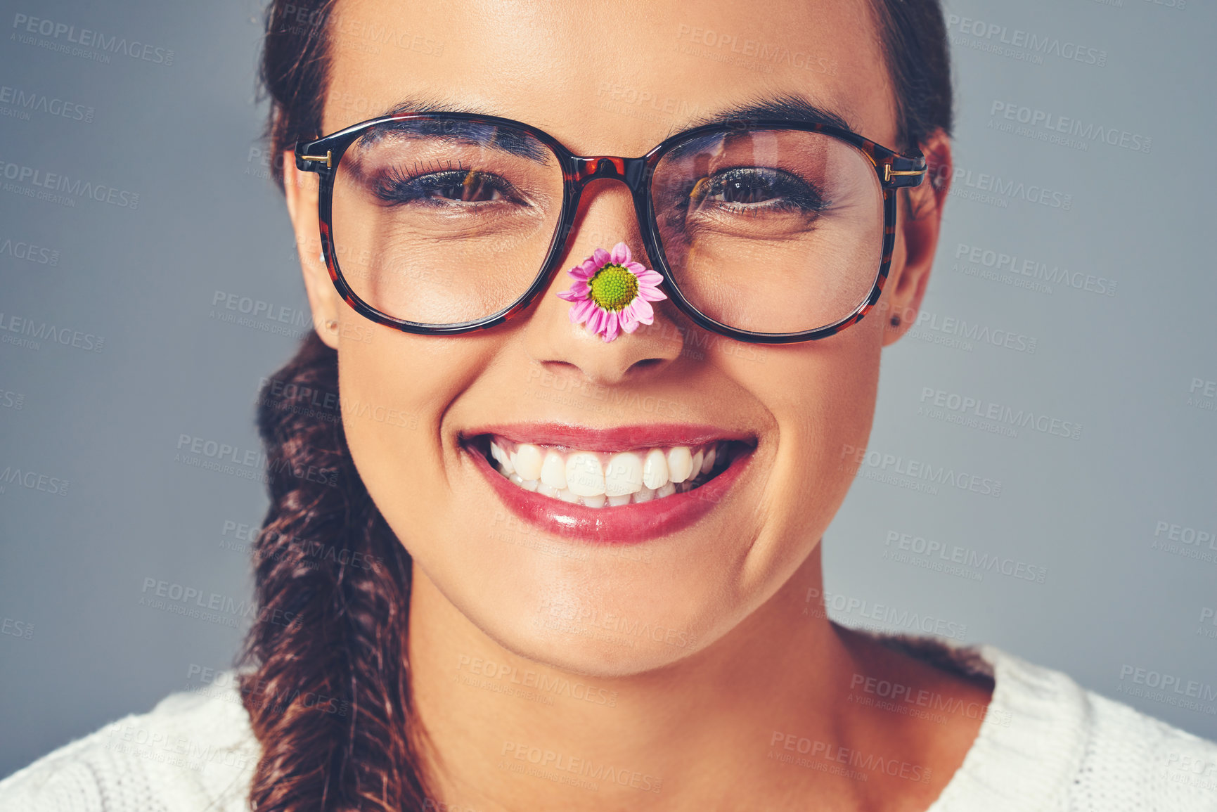 Buy stock photo Studio shot of a young woman with a flower on the tip of her nose