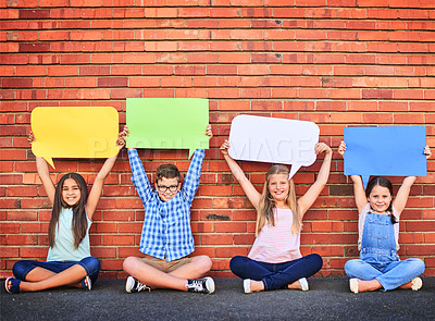 Buy stock photo Portrait of a group of young children holding speech bubbles against a brick wall