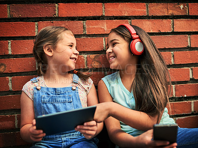 Buy stock photo Shot of two young girls using digital devices against a brick wall