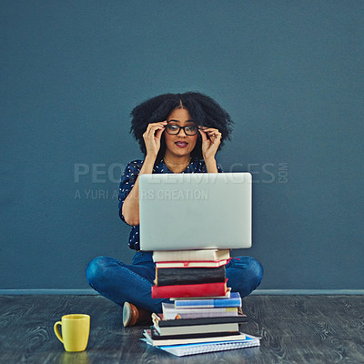 Buy stock photo Studio shot of a young woman using a laptop with books stacked in front of her against a gray background