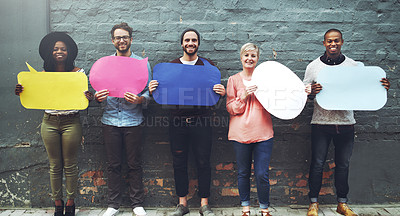 Buy stock photo Shot of a diverse group of people holding up speech bubbles against a gray brick wall