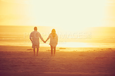 Buy stock photo Rearview shot of an affectionate mature couple walking hand in hand on the beach