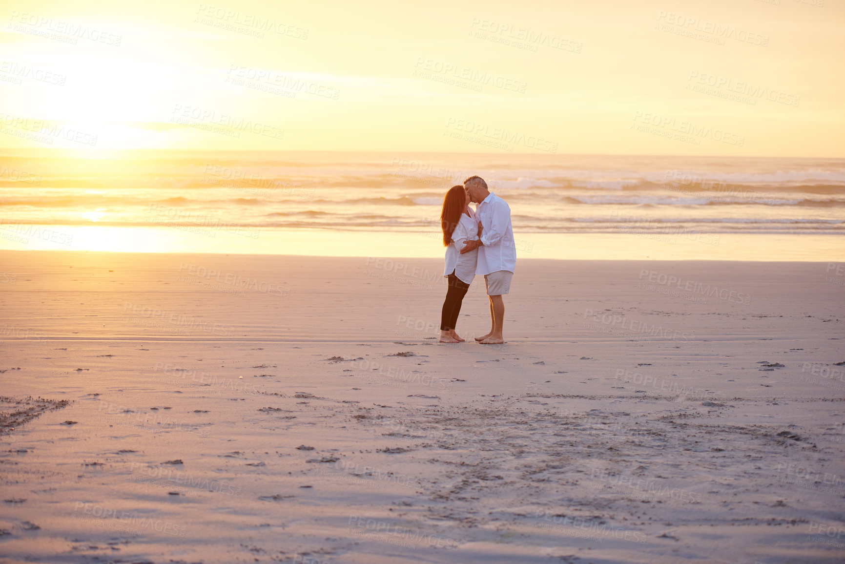 Buy stock photo Shot of a mature couple kissing on the beach