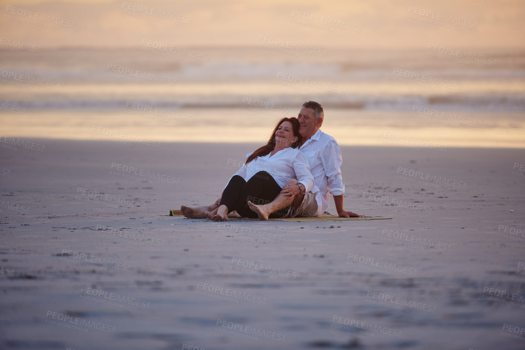 Buy stock photo Shot of a mature couple relaxing together on the beach