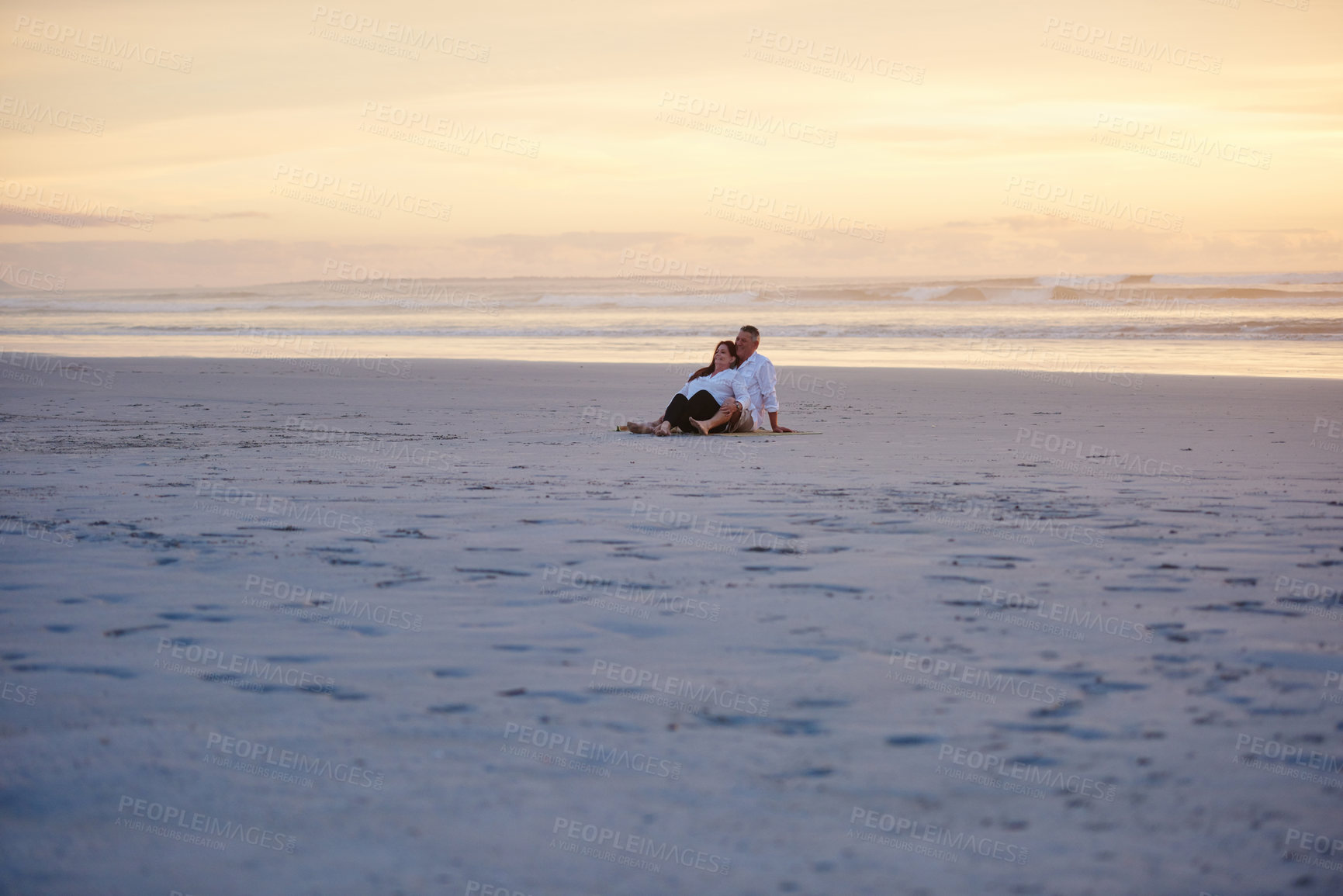 Buy stock photo Shot of a mature couple relaxing together on the beach