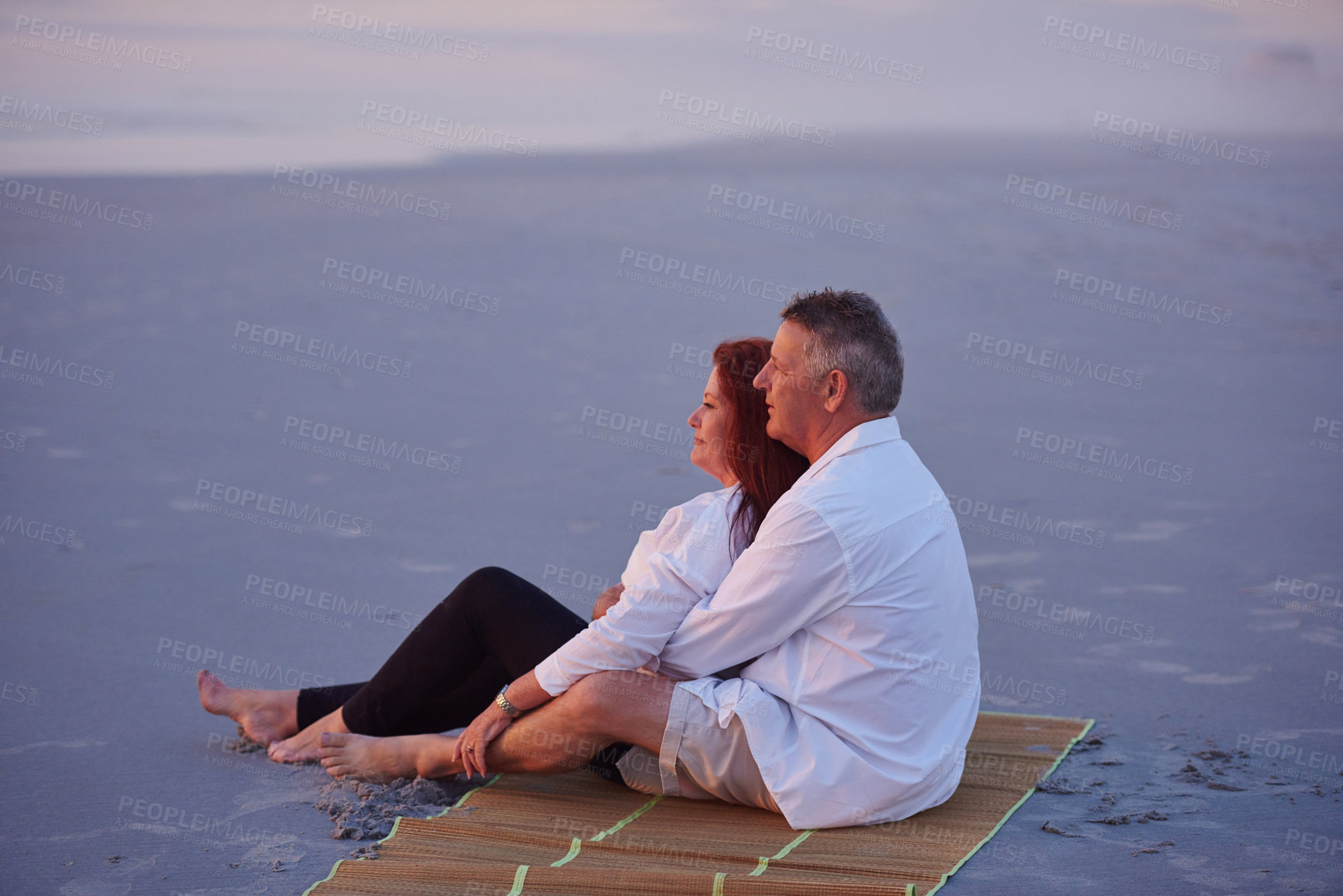 Buy stock photo Shot of a mature couple relaxing together on the beach