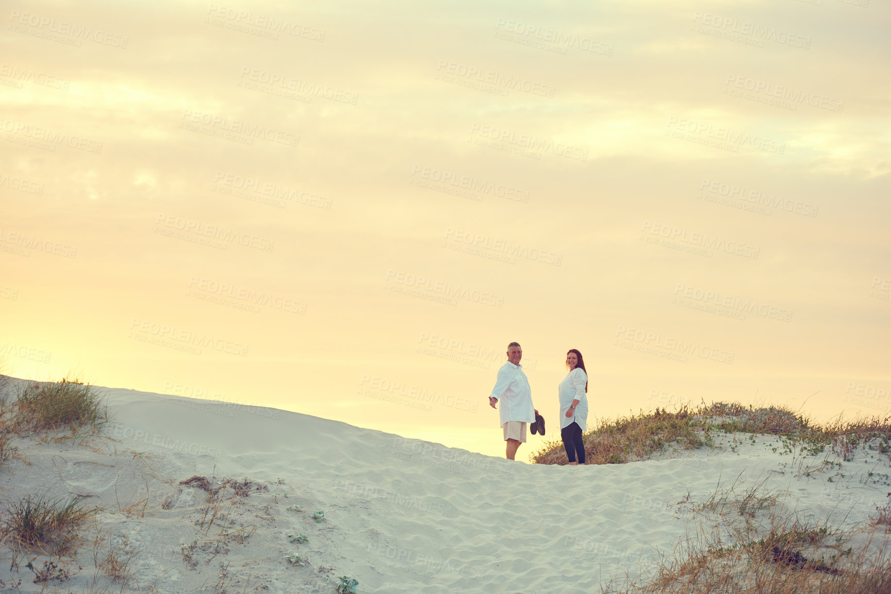 Buy stock photo Shot of mature people standing on a sand dune at the beach