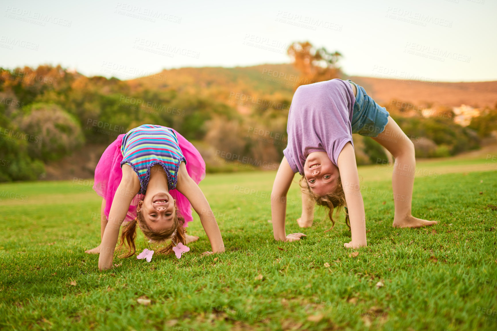 Buy stock photo Portrait of two little girls doing handstands on the grass outdoors