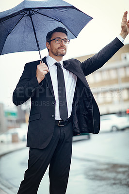 Buy stock photo Shot of a mature businessman holding an umbrella and gesturing to get a cab in the city