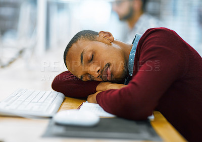 Buy stock photo Shot of a tired young man sleeping on a desk with his arms folded inside of a library