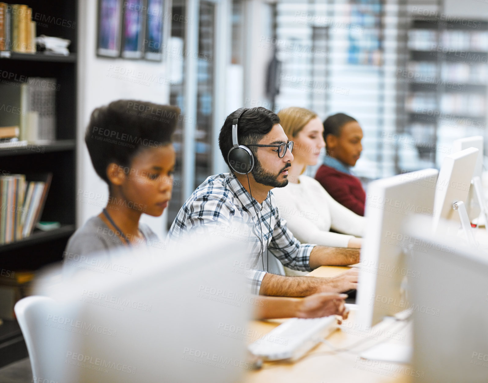 Buy stock photo Shot of a group of focused students working on computers  doing research for exams inside of a library