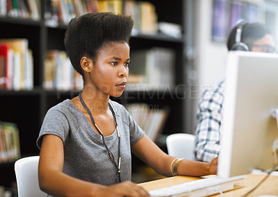 Buy stock photo Shot of a focused young woman working on a computer in a library