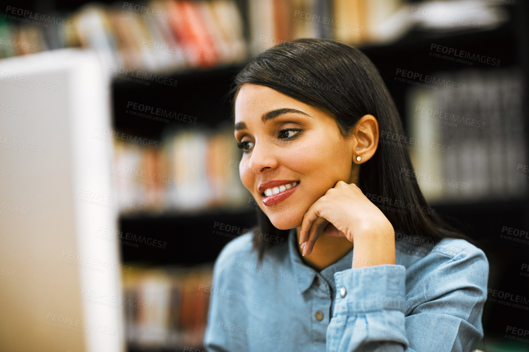 Buy stock photo Shot of a university student working on a computer in the library at campus