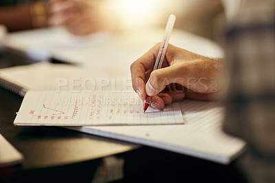 Buy stock photo Shot of a unrecognizable student writing down notes while being seated indoors
