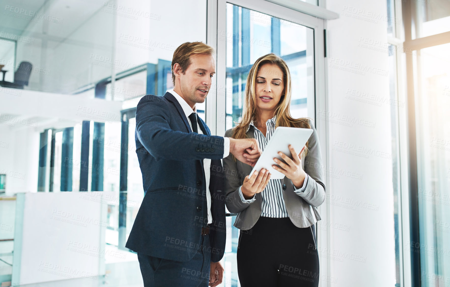 Buy stock photo Shot of two businesspeople discussing something on a digital tablet