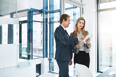 Buy stock photo Shot of two businesspeople discussing something on a digital tablet