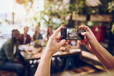 Buy stock photo Cropped shot of a man taking a picture of friends out for lunch