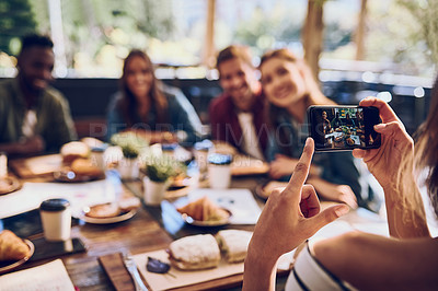 Buy stock photo Cropped shot of a woman taking a picture of colleagues having a business lunch