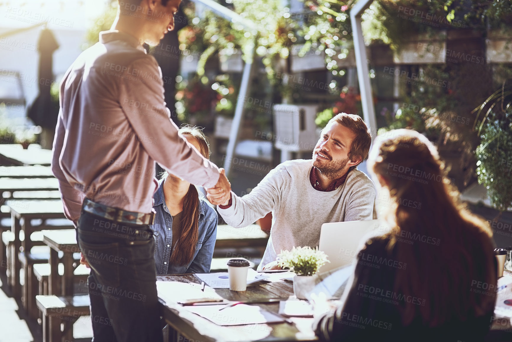 Buy stock photo Shot of colleagues shaking hands during a meeting at an outdoor cafe