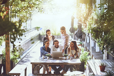Buy stock photo Shot of a team of colleagues using a laptop together during a meeting at an outdoor cafe