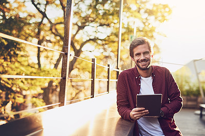 Buy stock photo Cropped shot of a handsome man using his digital tablet outside