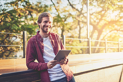 Buy stock photo Cropped shot of a handsome man using his digital tablet outside