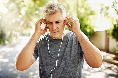 Buy stock photo Fit, mature and healthy or sporty athlete resting after morning run, listening to music outdoors with earphones. Male jogger about to exercise or do cardio training workout for wellness lifestyle.
