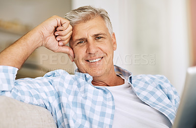 Buy stock photo Mature man relaxing, smiling and sitting on his sofa at home on vacation. Older guy comfortable on couch, cheerful and reading at home while on holiday. Happy, retired male enjoying his leisure time.