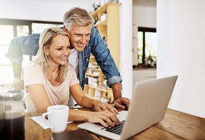 Buy stock photo Happy, smiling and mature couple using a laptop together at home. Charming husband assisting wife with online work on the internet. Cheerful Middle aged partners working as a team on social media.