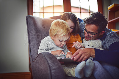 Buy stock photo Shot of a father using a digital tablet with his little son and daughter at home