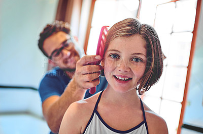 Buy stock photo Shot of a father combing his little daughter's hair at home