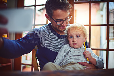Buy stock photo Shot of a father taking a selfie with his little son at home