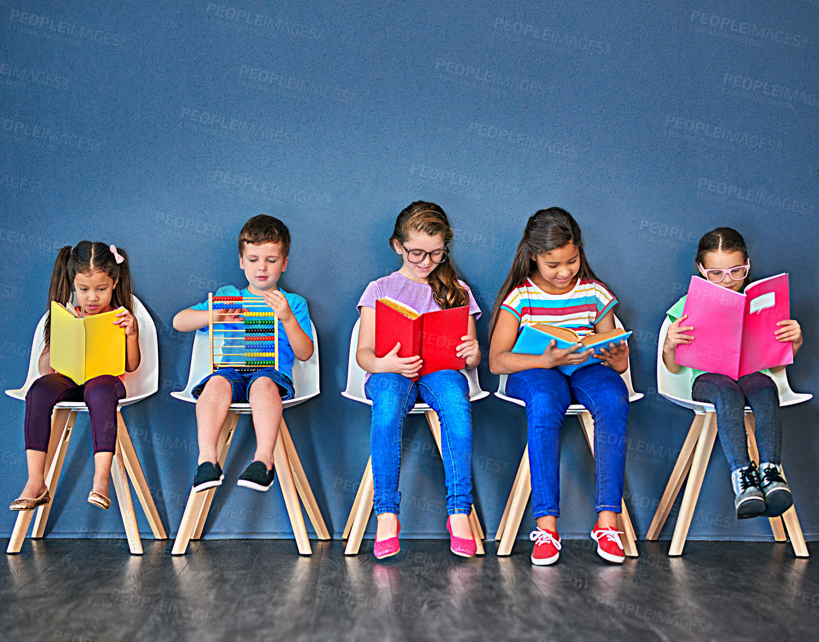 Buy stock photo Education, kids and students with books in studio for knowledge, development and studying for exam. Chair, row and children reading with paper for school, scholarship and learning for academic growth