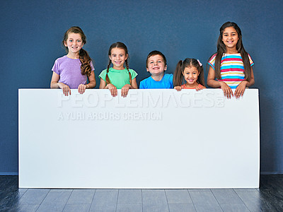 Buy stock photo Children, happy and portrait in studio for placard, advertising and marketing with mockup space. People, smile and face on blue background for banner, branding and presentation with logo information