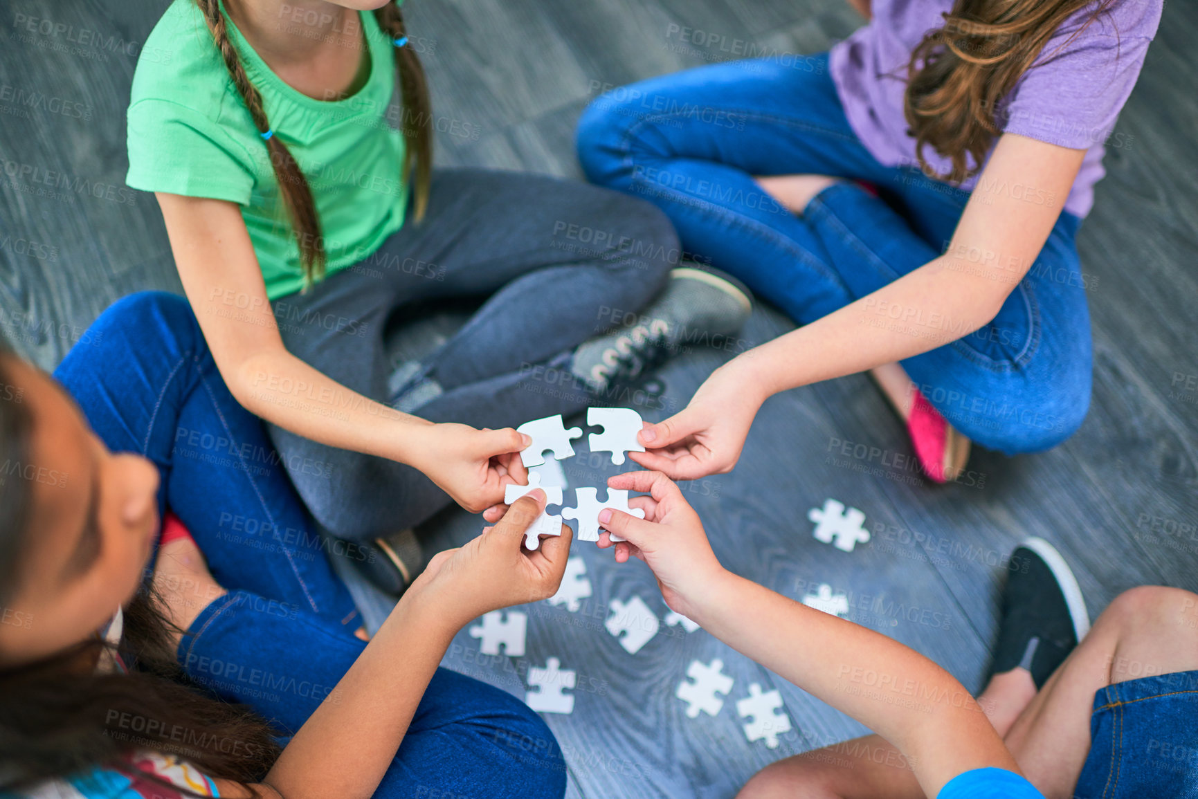 Buy stock photo Above, kids and game with puzzle for playing, cognitive development and solution skills by floor. Teamwork, children and solidarity with jigsaw for problem solving, support and friends for bonding