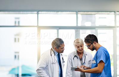 Buy stock photo Shot of a team of doctors using a digital tablet together in a hospital