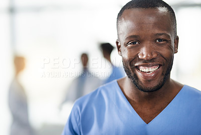 Buy stock photo Happy, smiling and professional doctor in a hospital closeup portrait with blurred background. Confident black male medical healthcare worker with colleagues in the back. An African American surgeon.