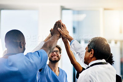 Buy stock photo Shot of a diverse team of doctors giving each other a high five in a hospital