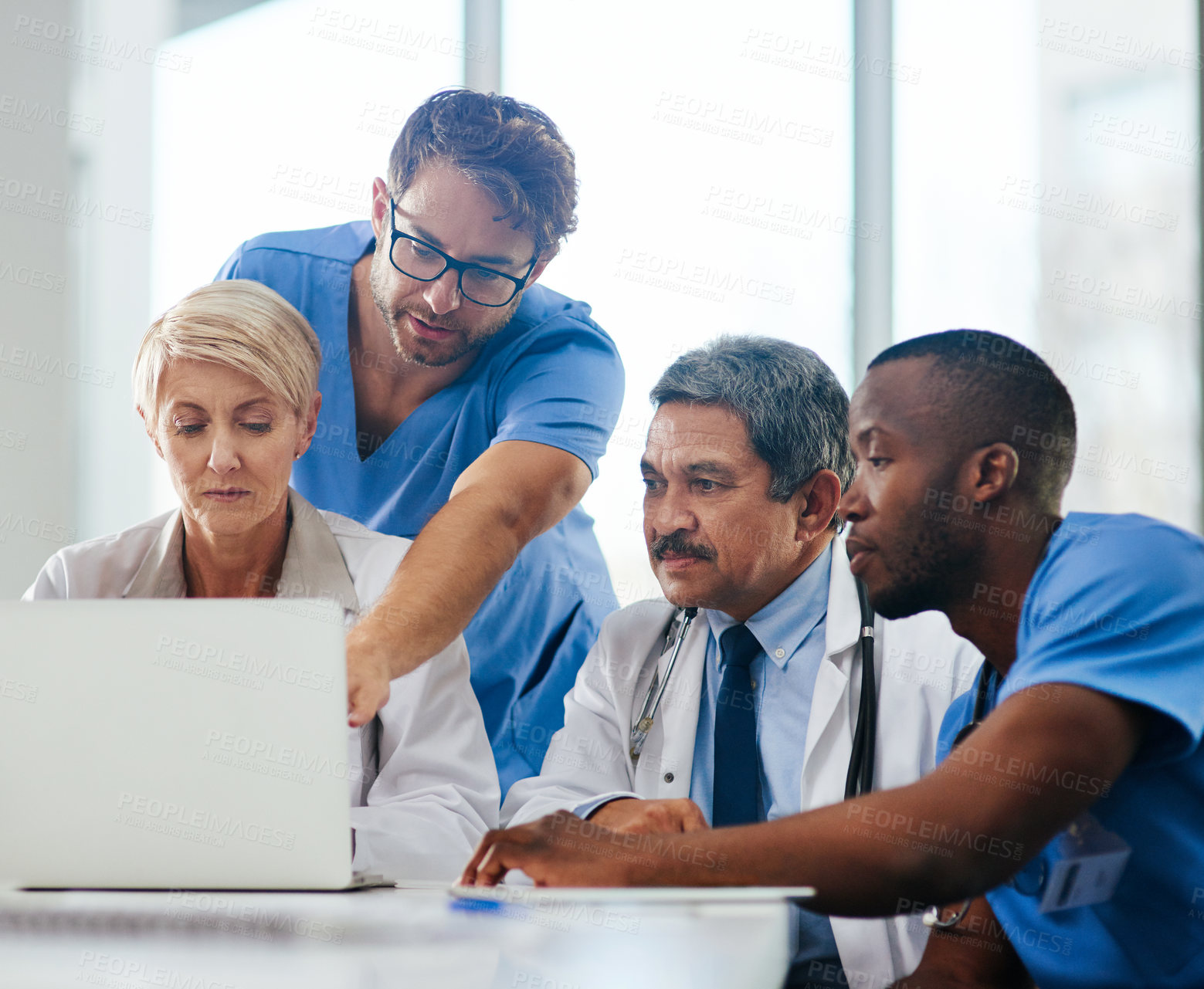 Buy stock photo Shot of a team of doctors using a laptop together during a meeting