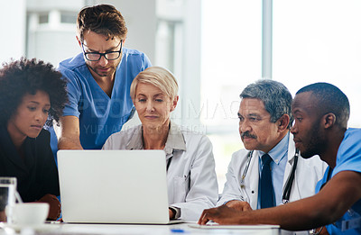 Buy stock photo Shot of a team of doctors using a laptop together during a meeting