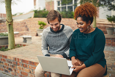 Buy stock photo High angle shot of two young university students using a laptop to study on campus