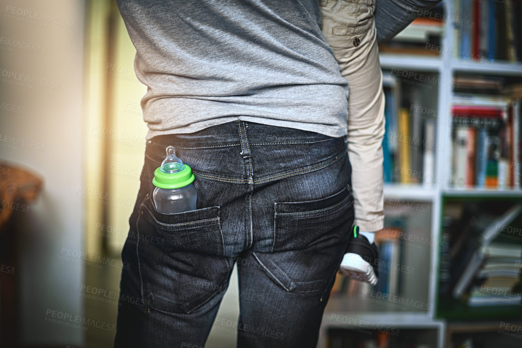 Buy stock photo Rearview shot of an unrecognizable single father with a bottle in his pocket at home