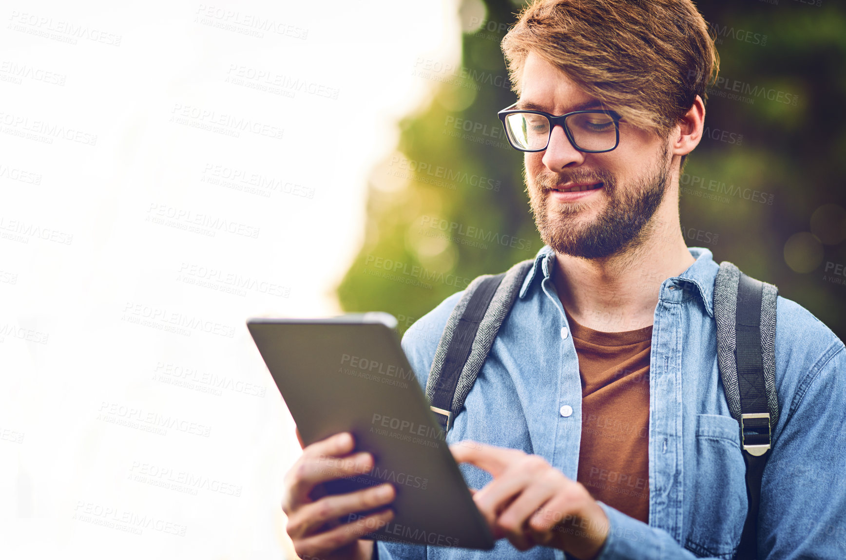 Buy stock photo Cropped shot of a handsome young man using a tablet outdoors